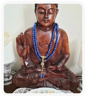 Wooden Buddha statue draped in a Lapis Lazuli mala necklace