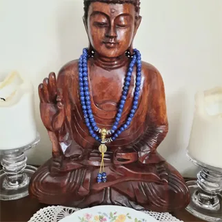 Wooden Buddha statue wearing a Lapis Lazuli mala, close-up